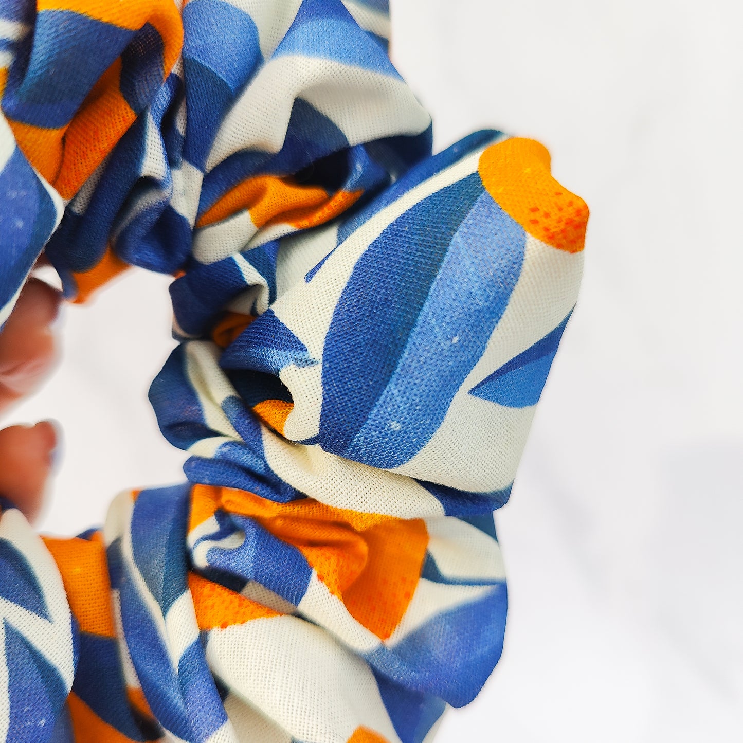 Colorful scrunchie with blue, orange, and white pattern on a white background