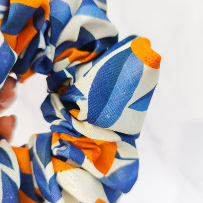 Colorful scrunchie with blue, orange, and white pattern on a white background